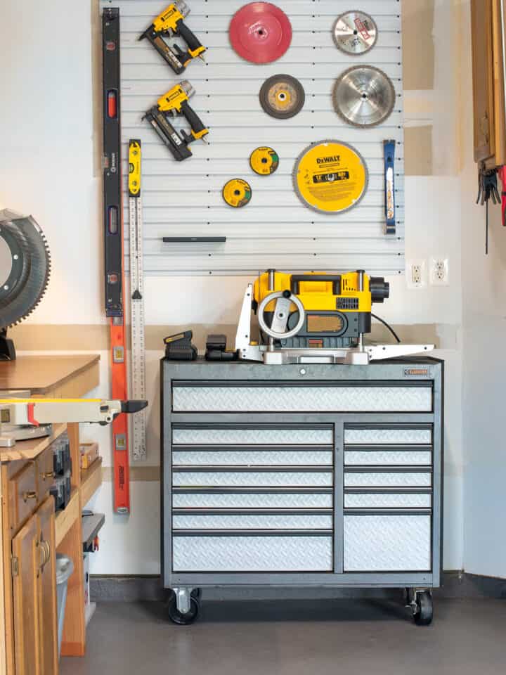Organized garage with workbench, tool chest, and slatwall pegboard above tool chest.
