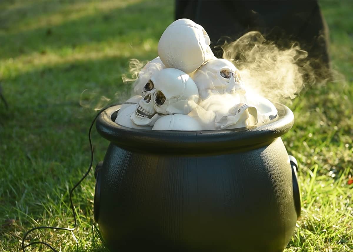 A cauldron filled with skulls and smoke fog emitting from it.
