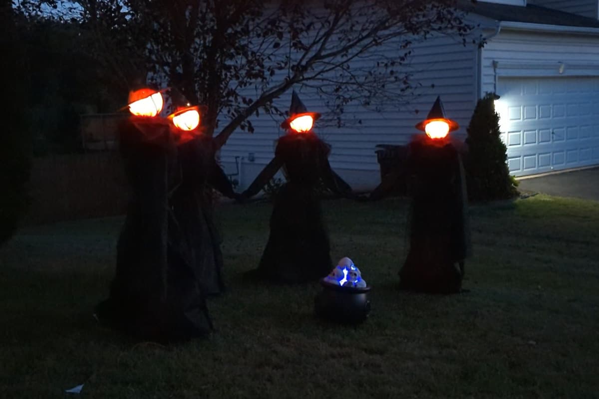 Glowing witches with light up heads in a circle and a cauldron.