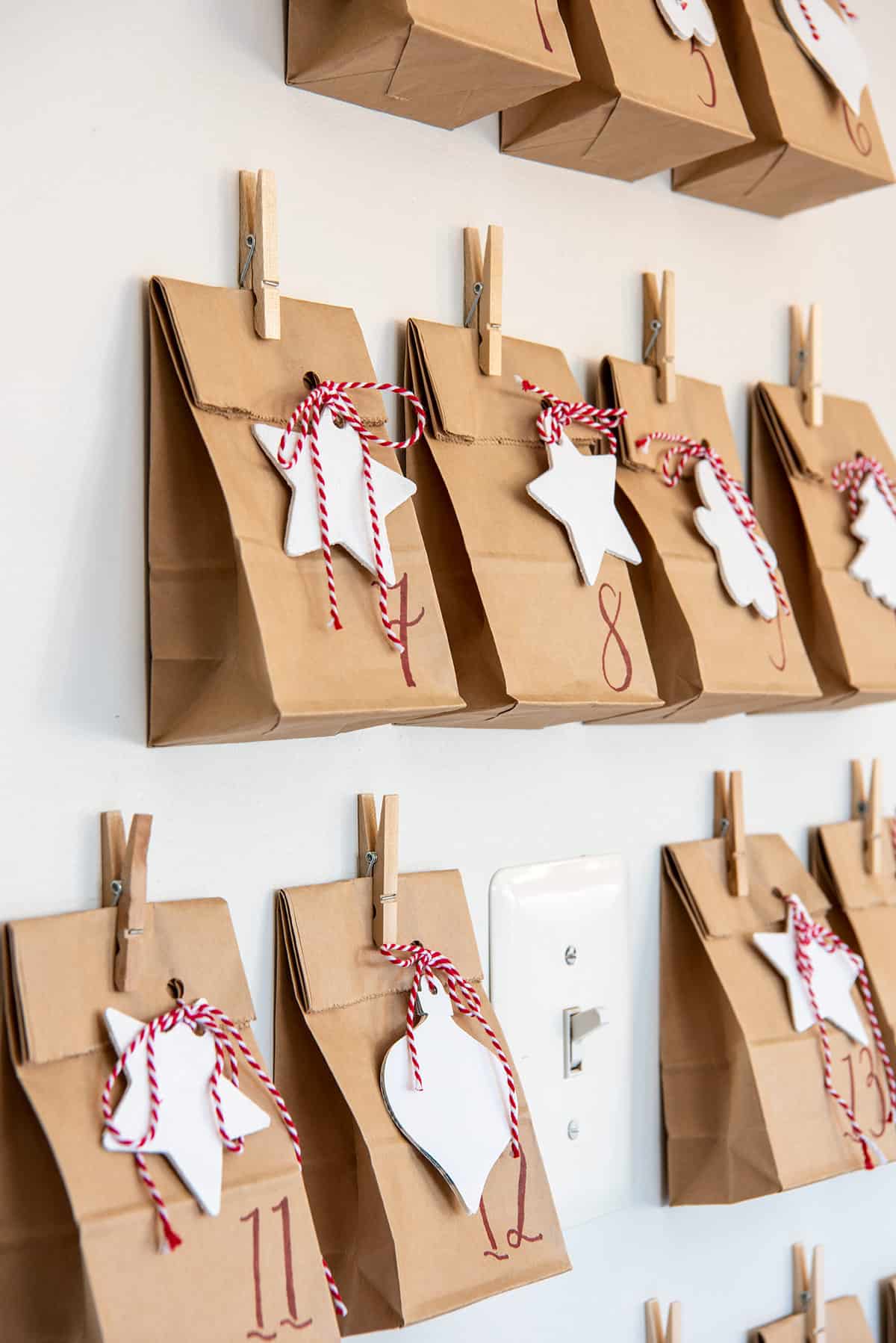 Closeup of simple paper bag advent calendar with cookie cutter shapes and red ribbon.