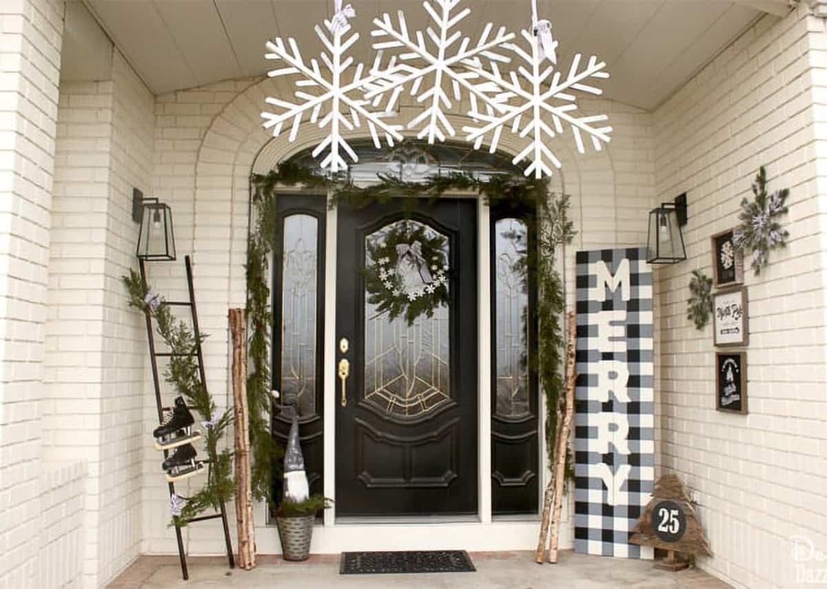 Black and white Christmas porch decorations with large snowflakes overhead and a buffalo plaid sign.