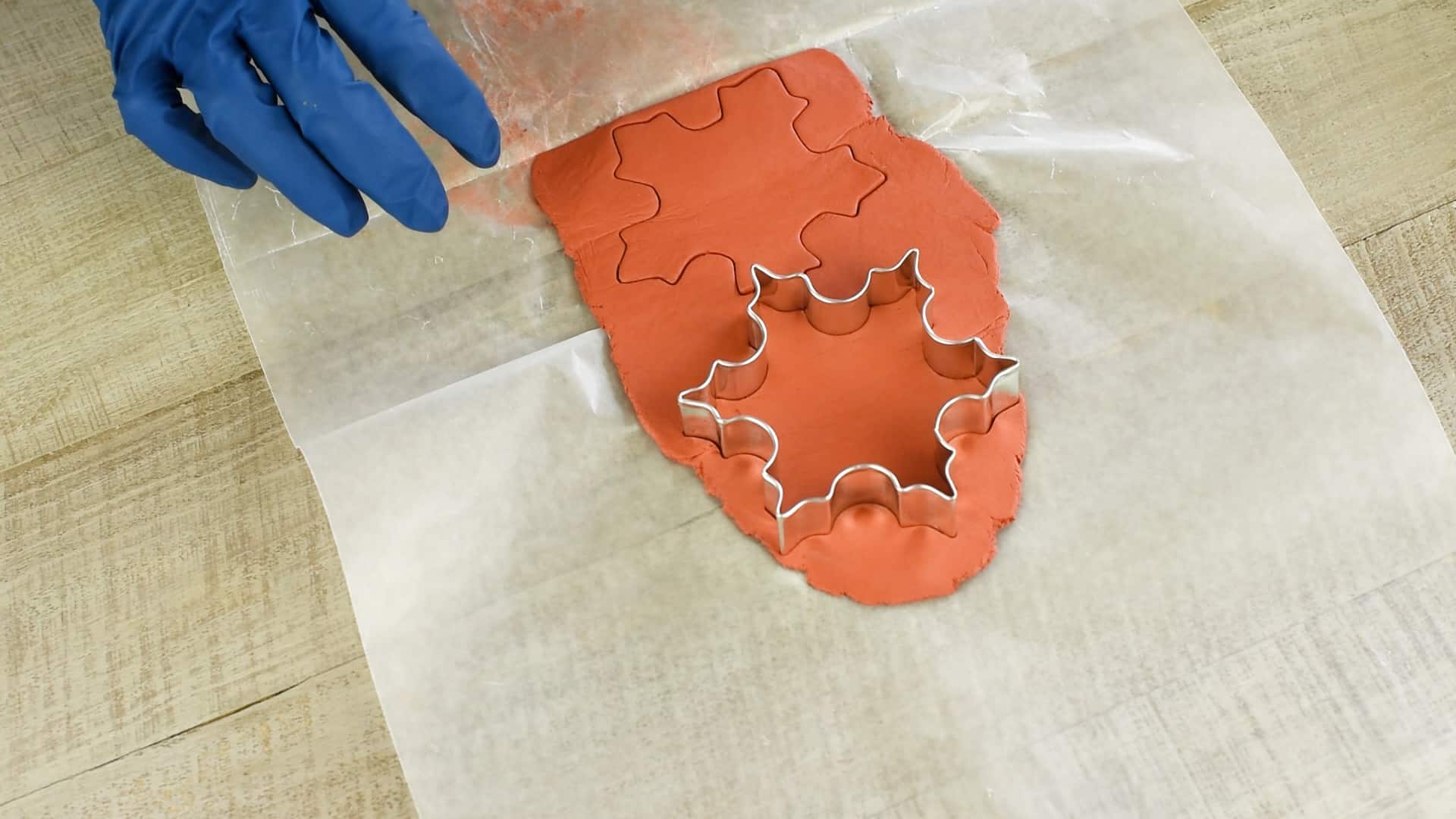 Closeup of using snowflake cookie cutter on clay dough.