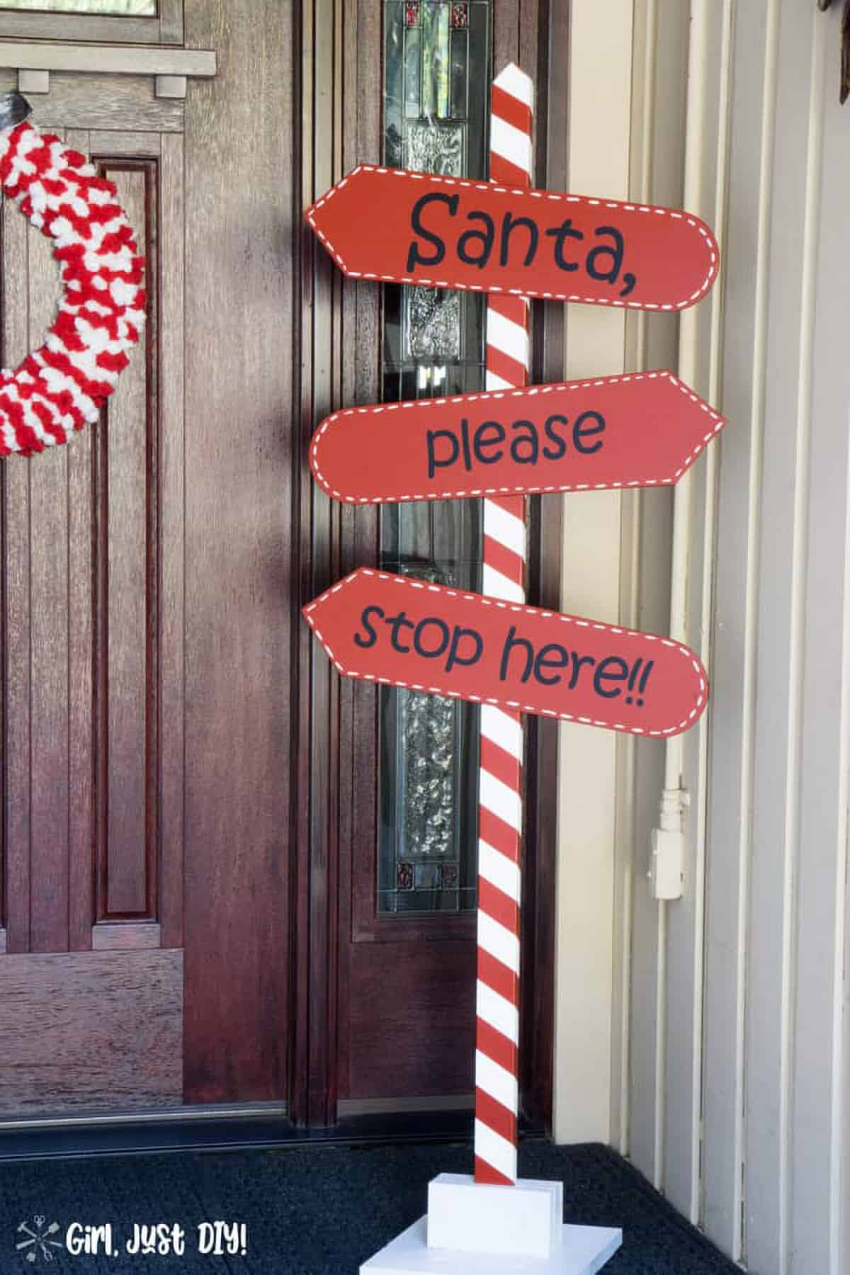 DIY Santa please stop here welcome sign with candy cane pole in front of door.