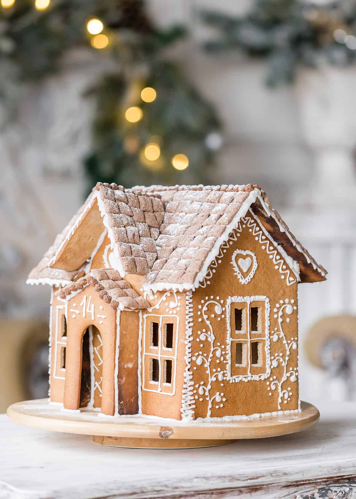 Homemade gingerbread house with white icing decorations on a table.