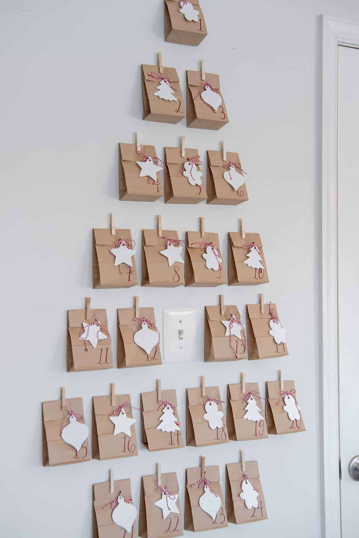 Paper bag advent calendar hung on the wall with a light switch in the center.