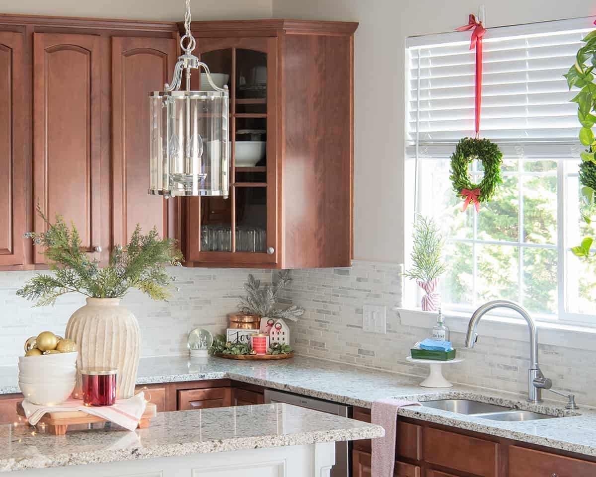 Countertops and kitchen island decorated for the holidays with wreaths, serving trays, and candles.