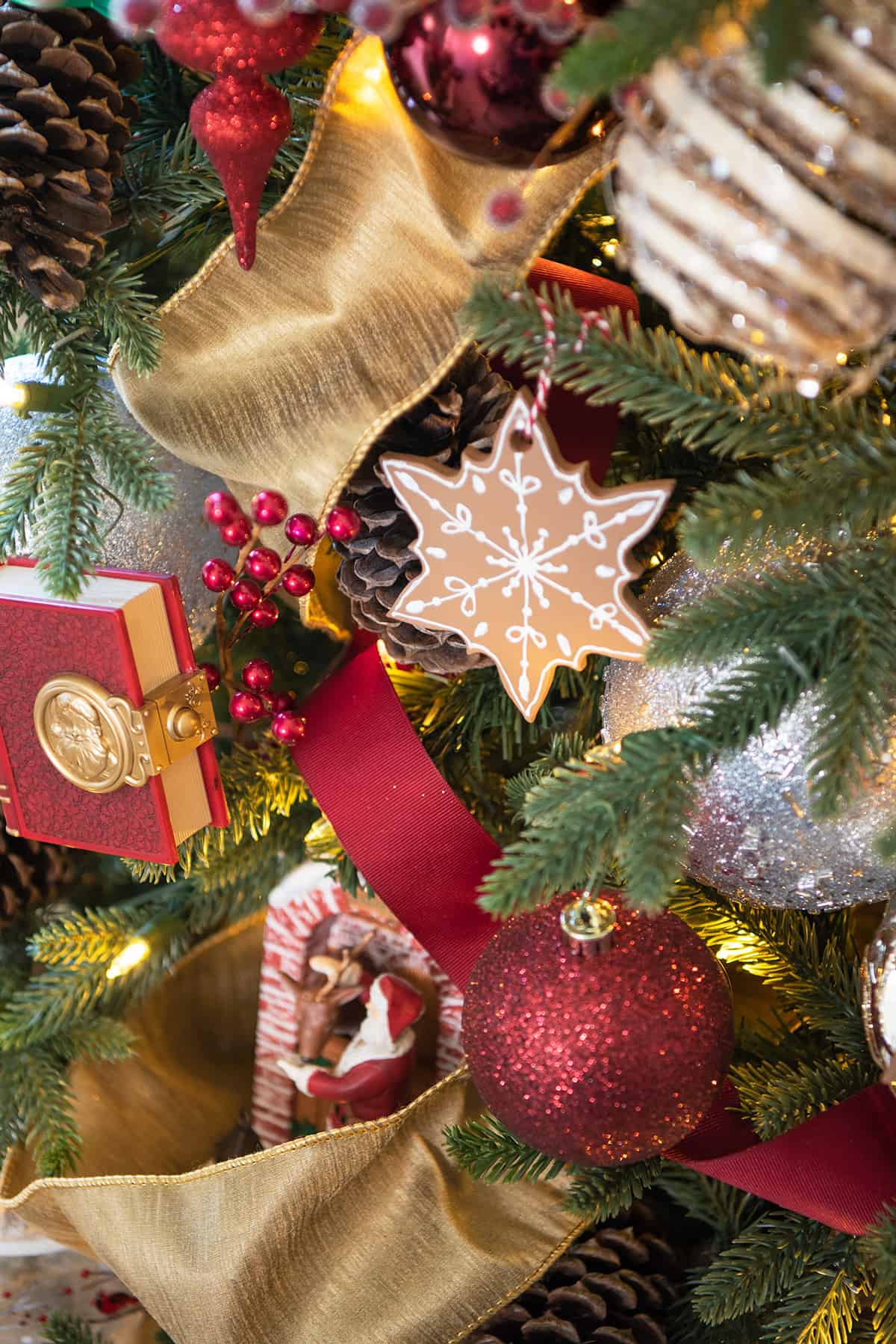 DIY gingerbread tree decoration that looks like a cookie surrounded by red and gold ribbon.