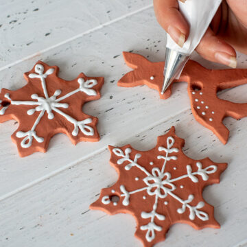 Adding Icing to gingerbread ornaments.