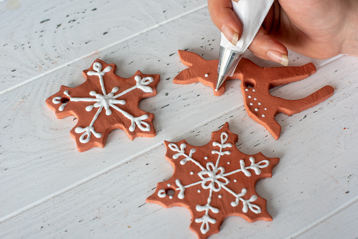 Adding Icing to gingerbread ornaments.