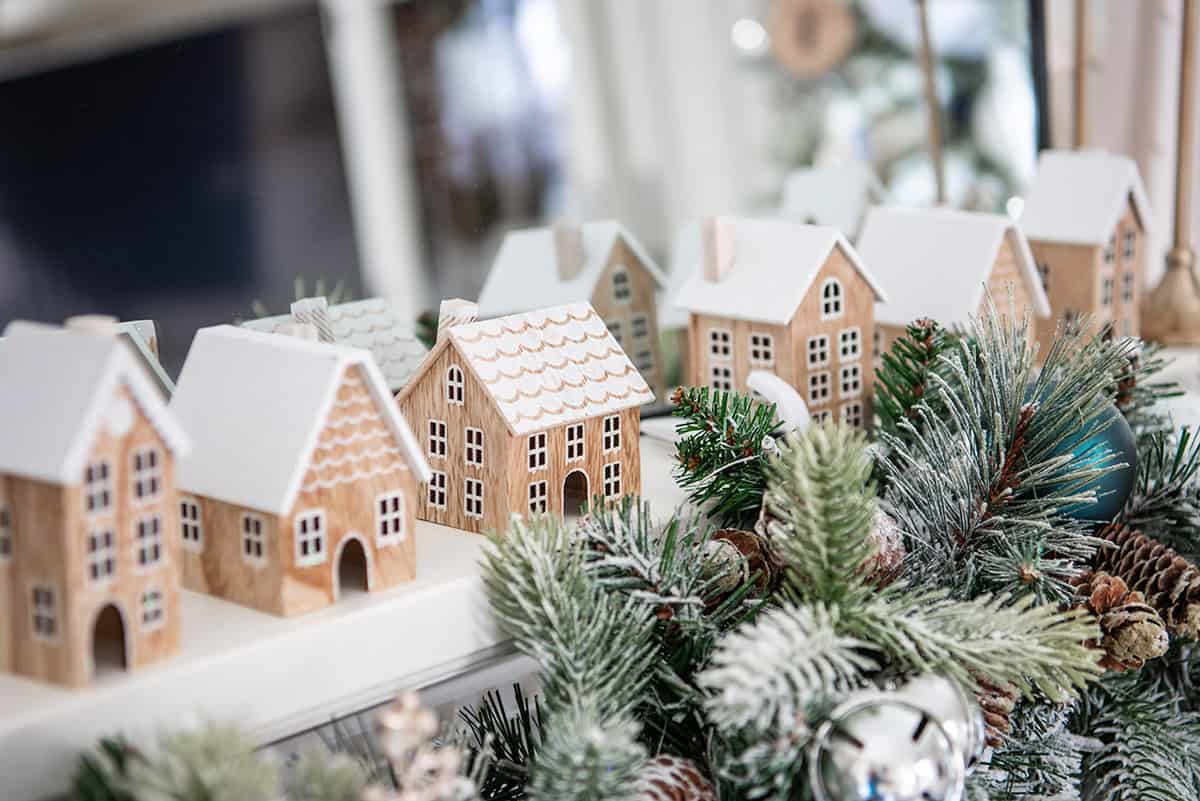 Several small wooden houses similar to gingerbread houses lined up on a fireplace.