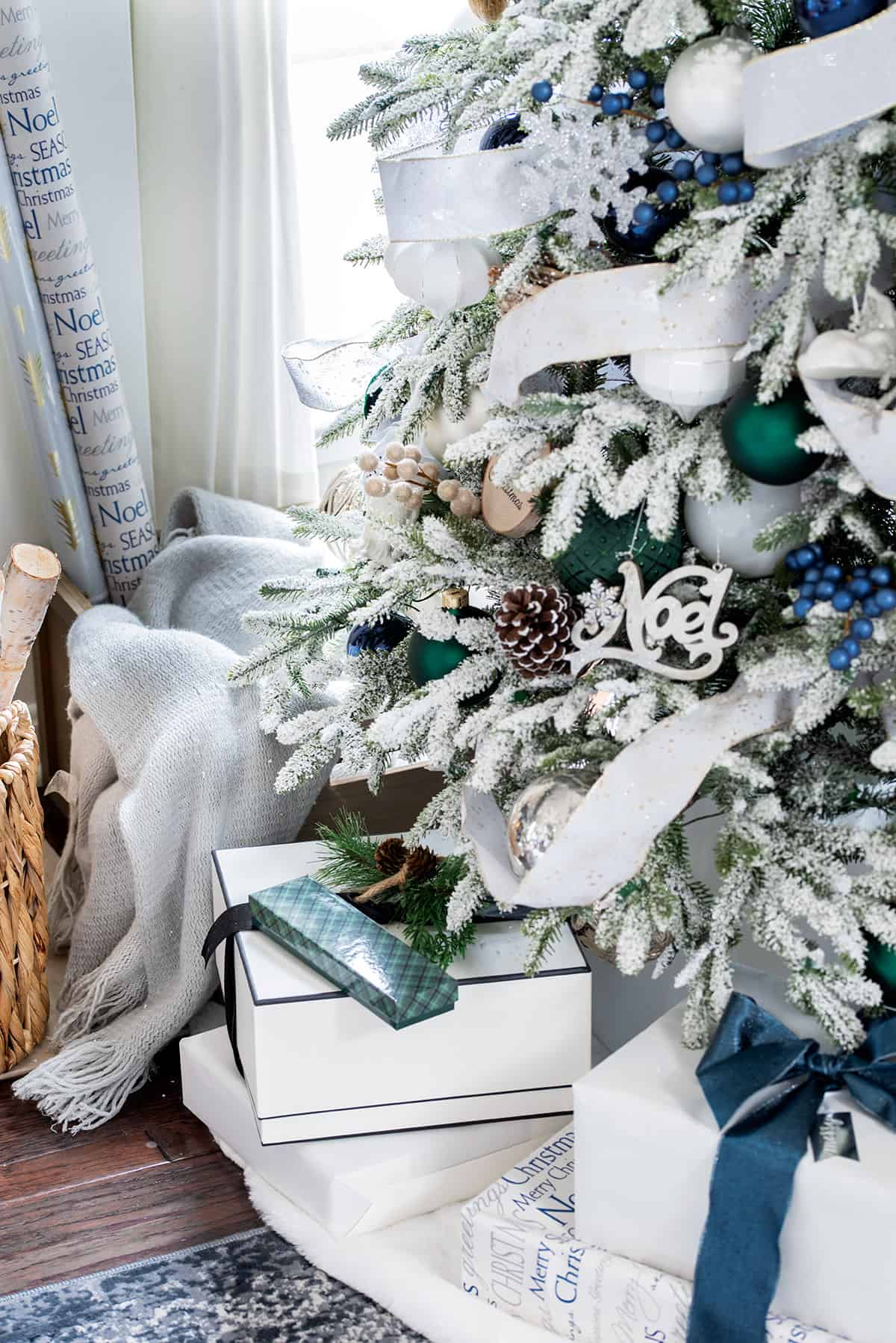 Closeup of white packages under a flocked Christmas tree.