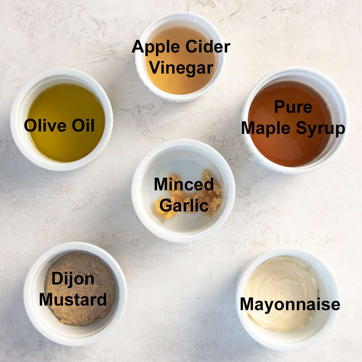 Ingredients for Maple Dijon dressing with apple cider vinegar, olive oil, maple syrup, Dijon mustard, and mayonnaise in bowls.