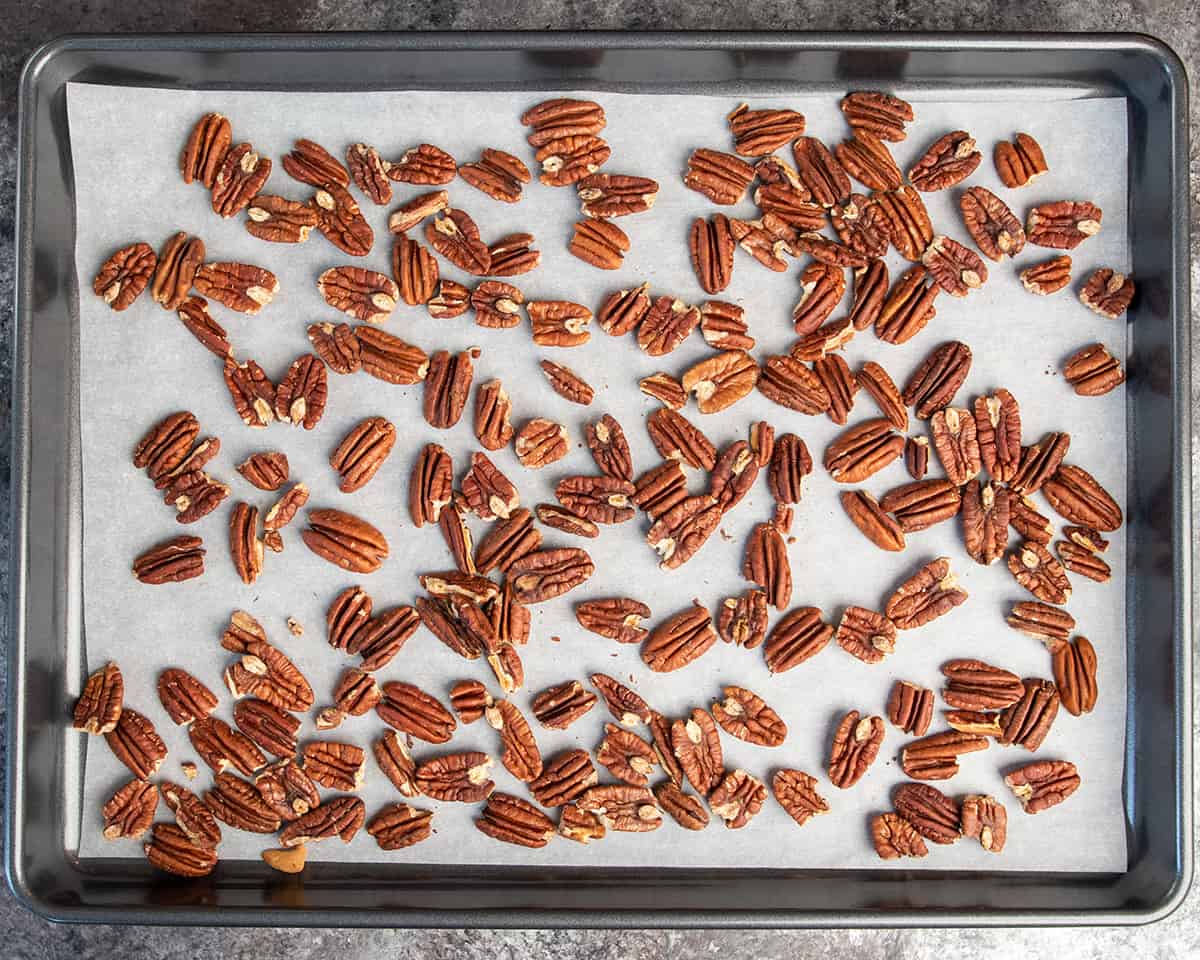 Overhead of toasted pecans on a cookie sheet with parchment paper.