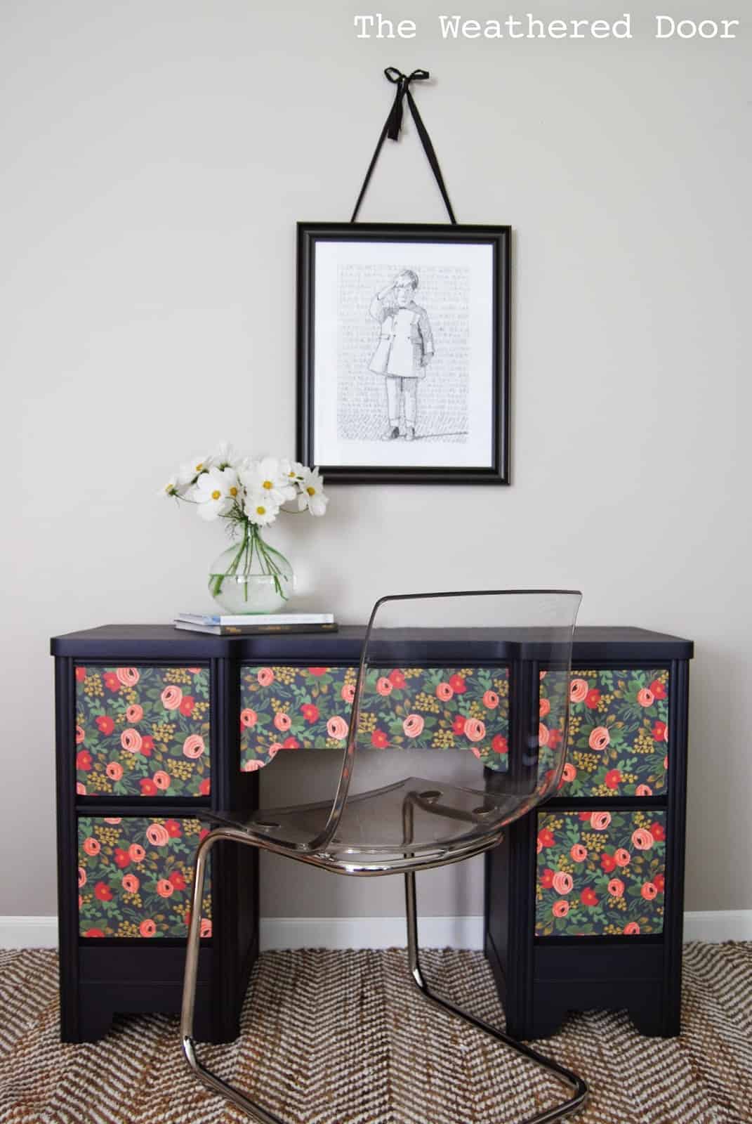Dark blue painted desk with floral wallpaper on the drawers.