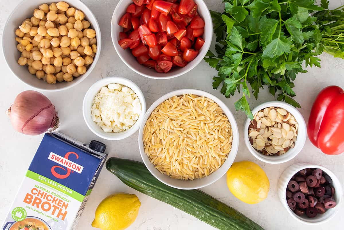 Ingredients for Mediterranean pasta salad laid out on a table. 