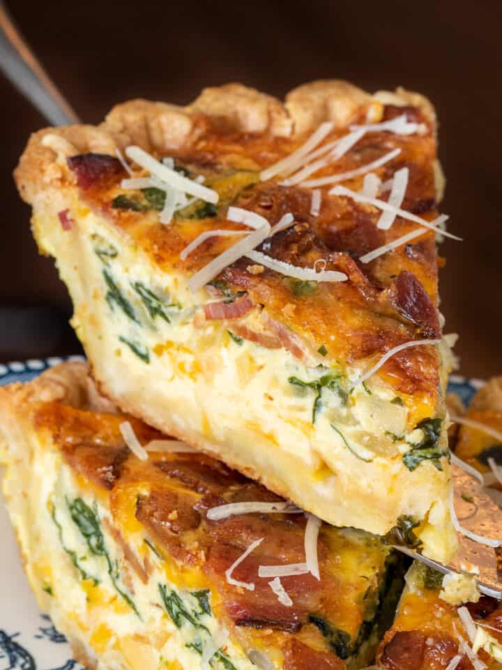 Slice of Spinach Bacon Quiche being pulled out of a full quiche showing the side for texture.