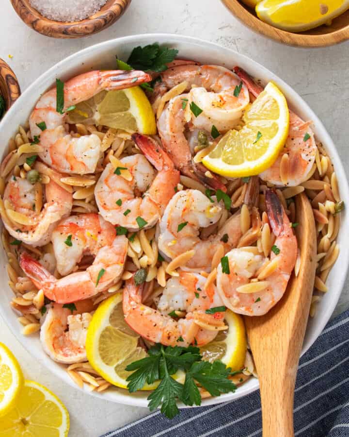 Overhead view of garlic lemon shrimp with orzo pasta in a bowl with a wooden spoon.