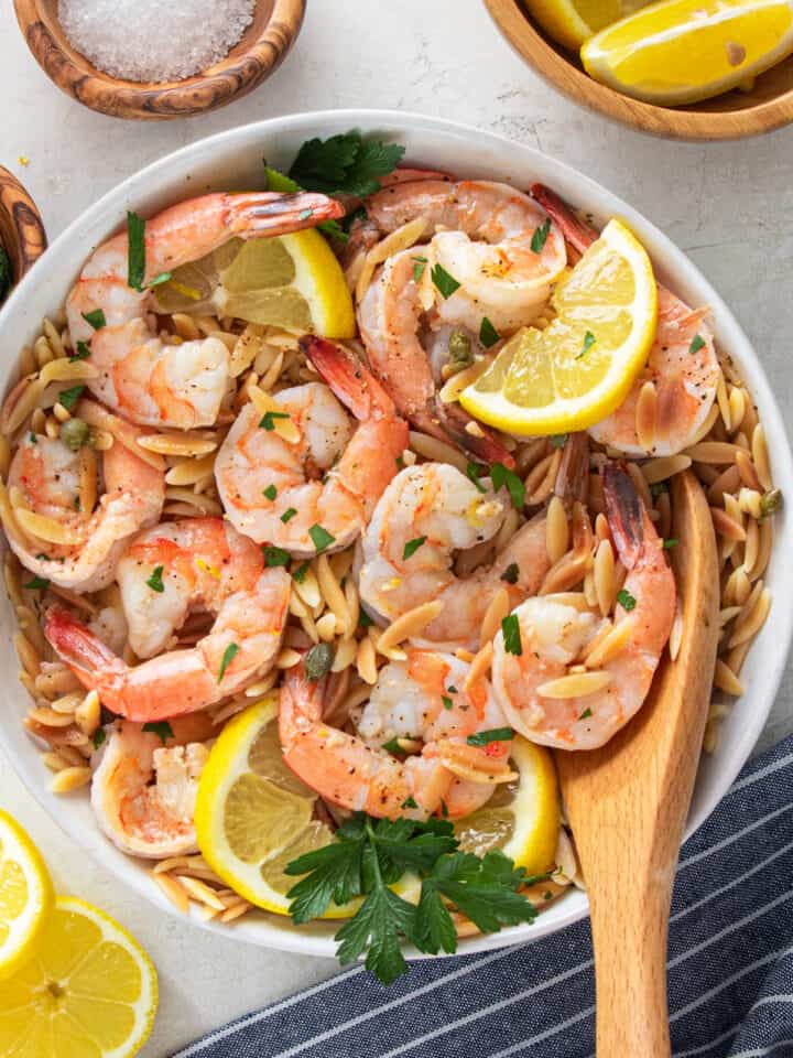 Overhead view of garlic lemon shrimp with orzo pasta in a bowl with a wooden spoon.