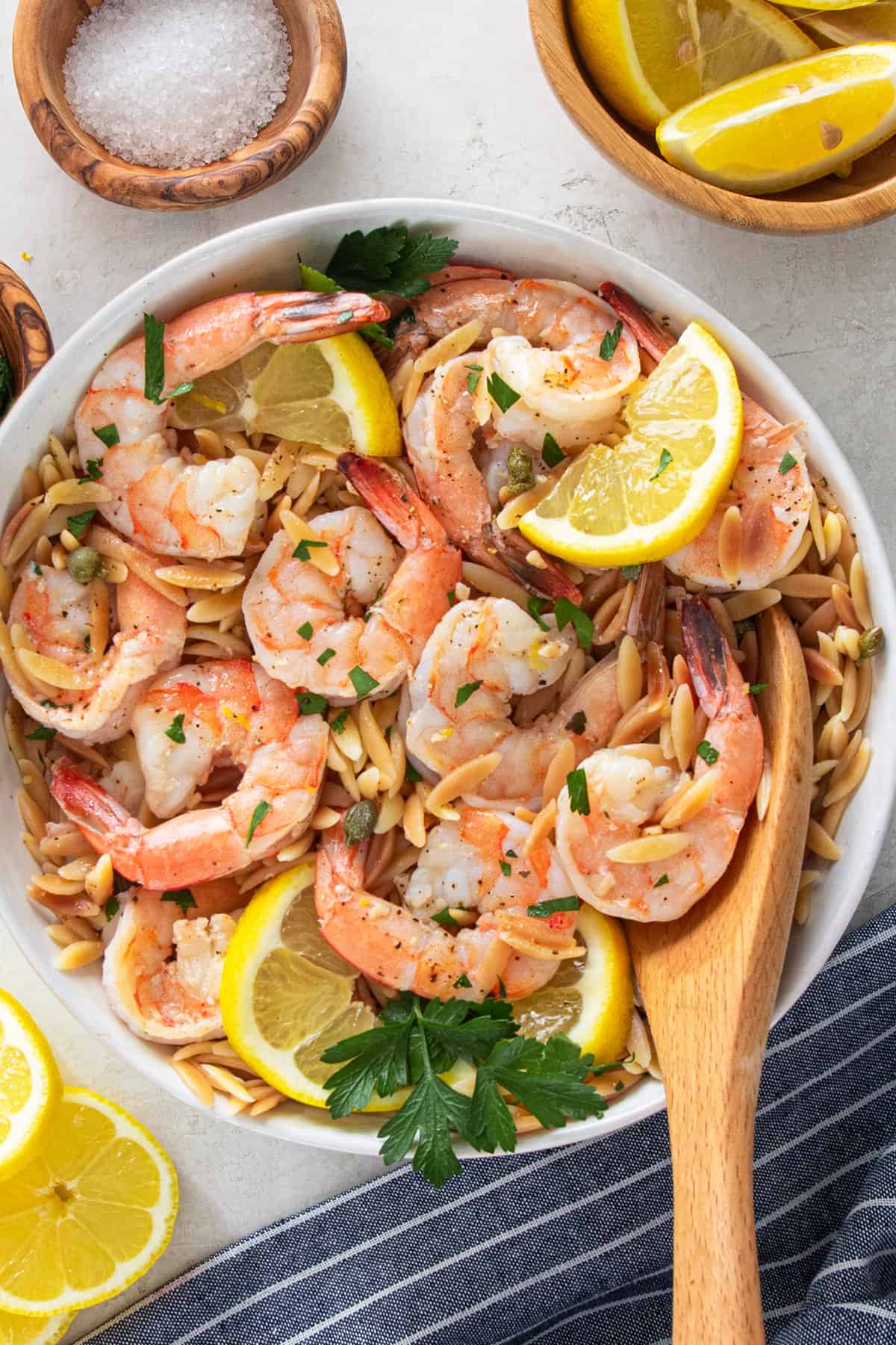 overhead view of garlic lemon shrimp with orzo pasta in a bowl with a wooden spoon.