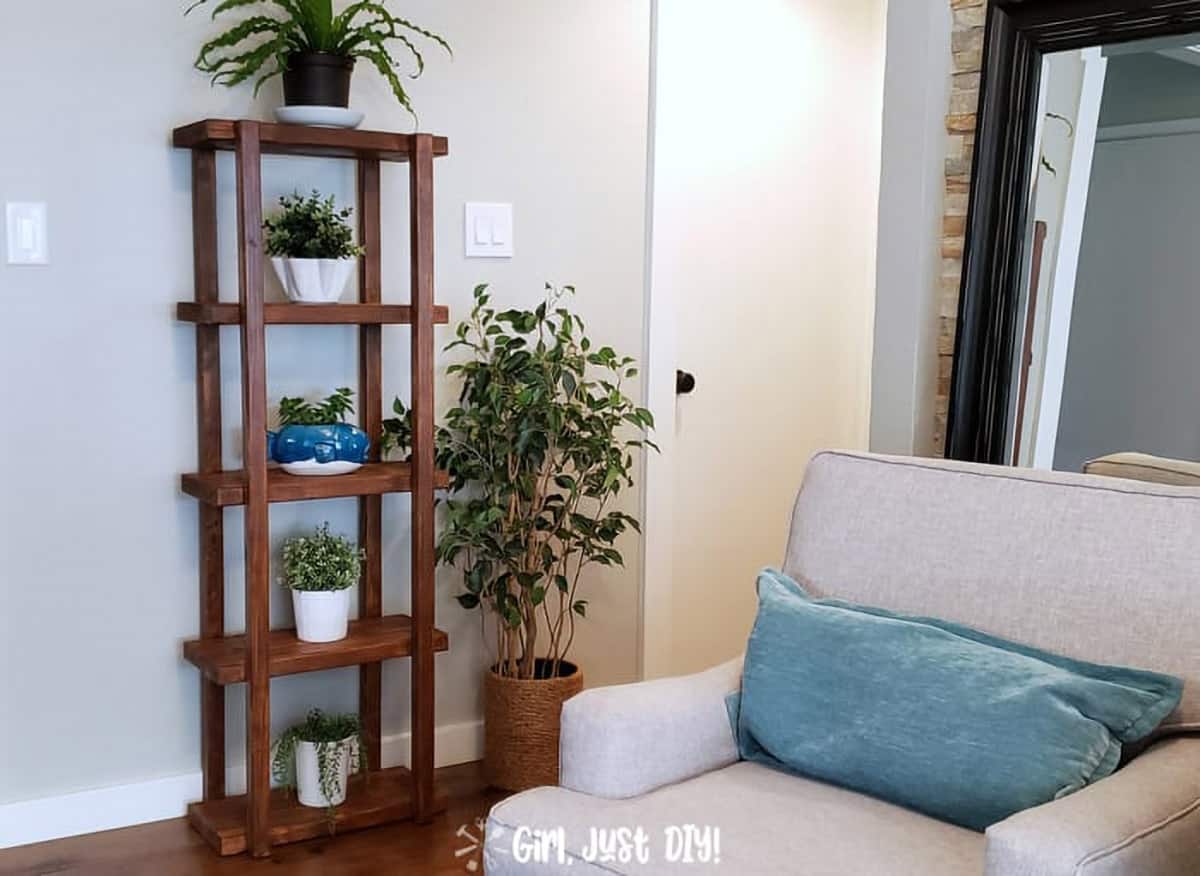 Dark stained wood DIY vertical tiered plant shelves against gray living room wall with four white potted plants.