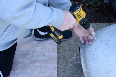 Man drilling a hole into a concrete planter with a concrete drill bit.