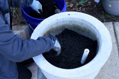 Woman adding dirt to planter.