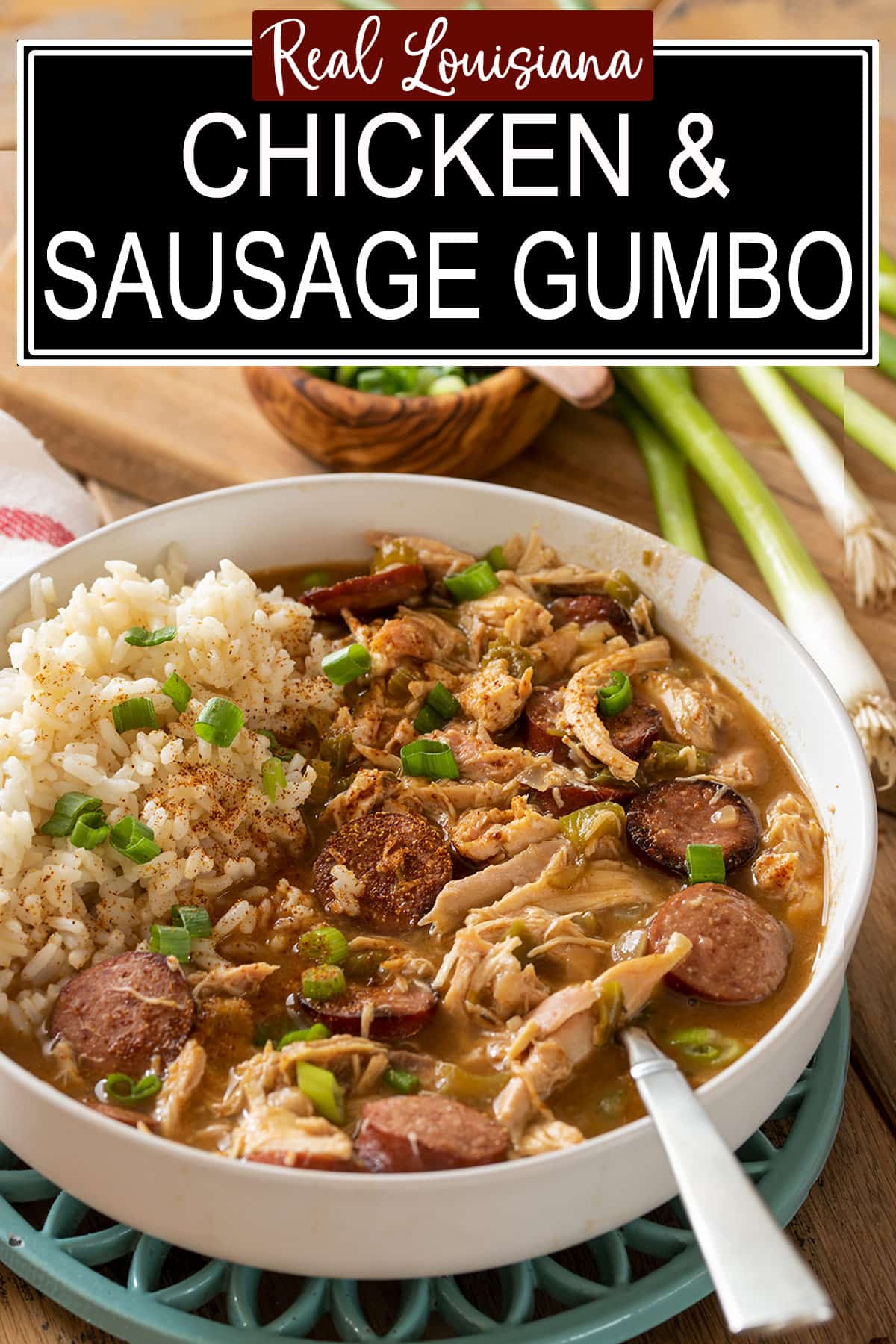 A bowl of chicken sausage gumbo with white rice on the side and a spoon.