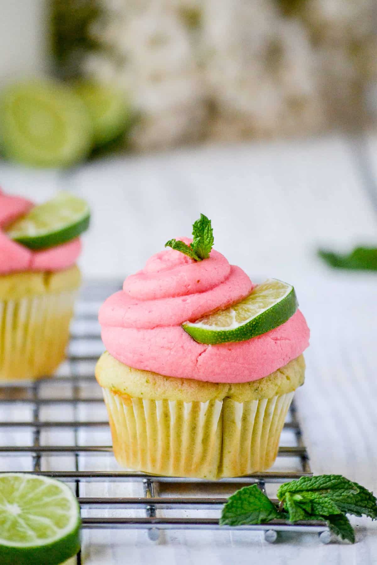 Summer Berry Mojito cupcake make a unique cupcake flavor idea with raspberry puree frosting and mint leaf and lime slice garnish.