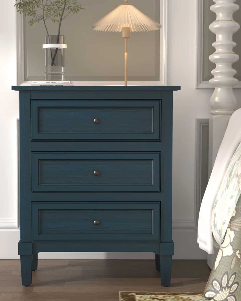 Navy blue 3 drawer slim nightstand next to a bed.