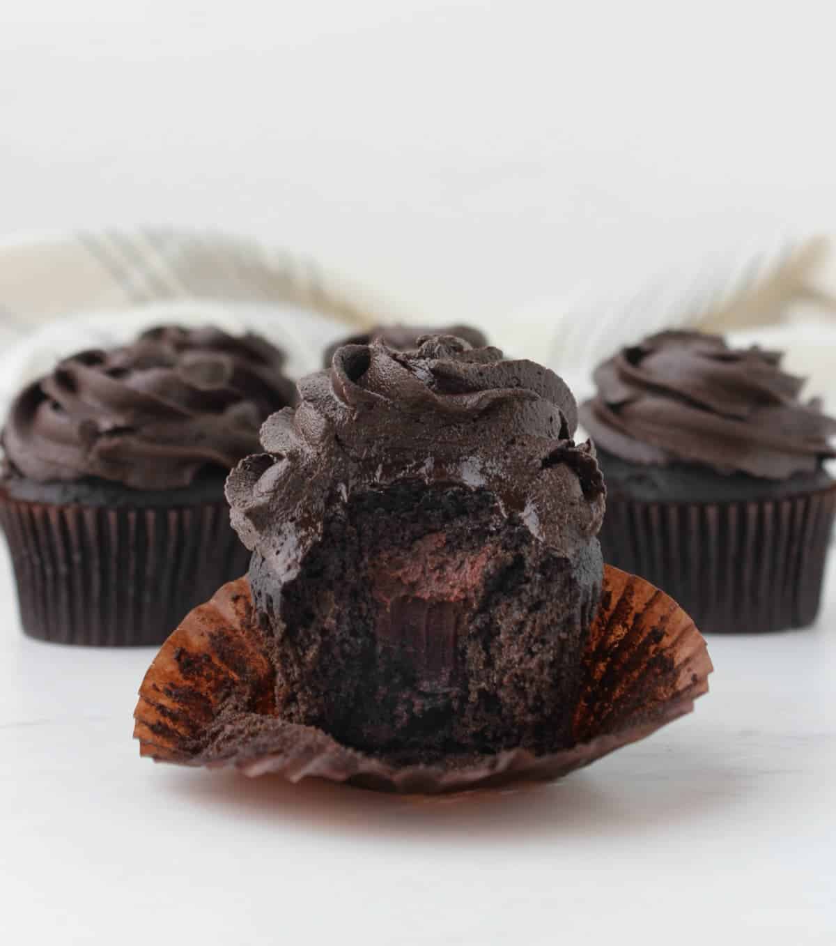 Death by chocolate cupcakes with one unwrapped to reveal layers of chocolate.