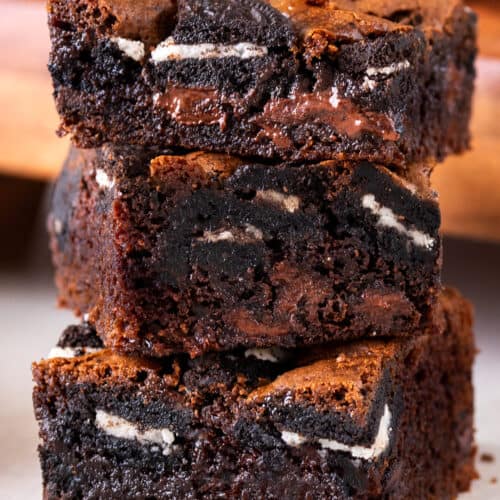 Fudgy Oreo Brownies with chocolate chips stacked high to show texture and oreo bits.