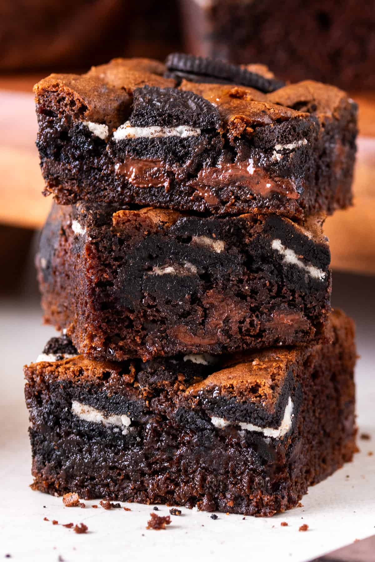 Fudgy Oreo Brownies with chocolate chips stacked high to show texture and oreo bits.