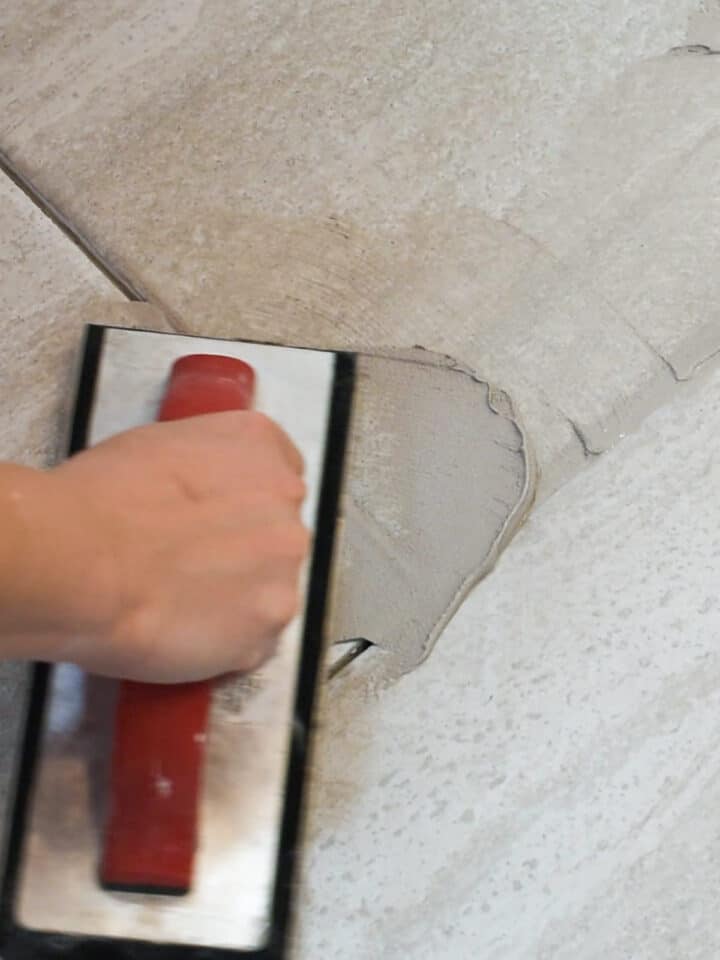 Closeup of someone adding grout to a tile floor