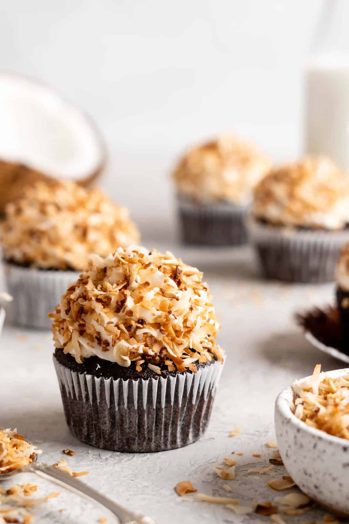 Chocolate Toasted Coconut Cupcakes features toasted coconut frosting and halved coconut in background.