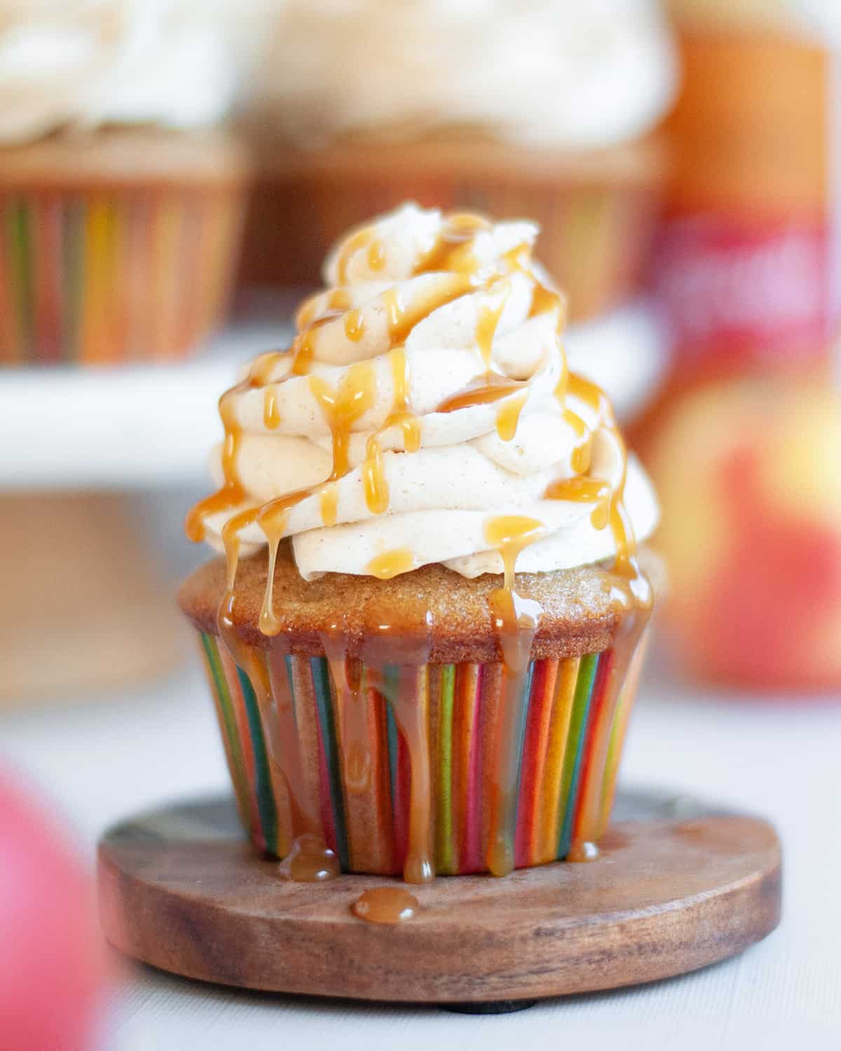 Apple cupcake with caramel sauce dripping over top whipped topping.