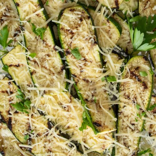 Grilled zucchini piled on foil and topped with shredded parmesan cheese.