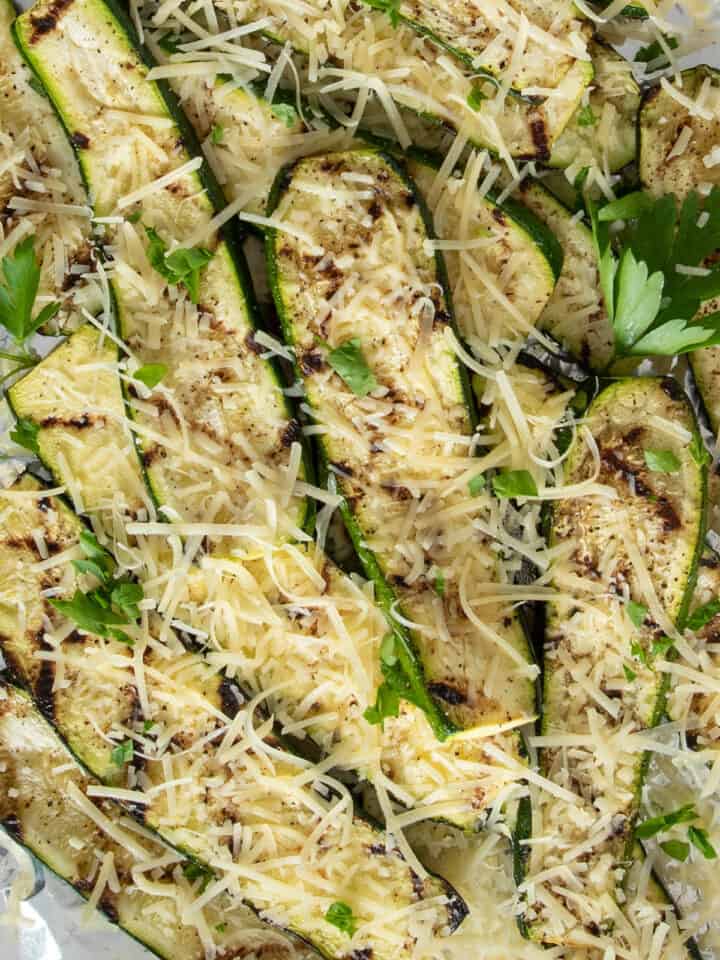 Grilled zucchini piled on foil and topped with shredded parmesan cheese.