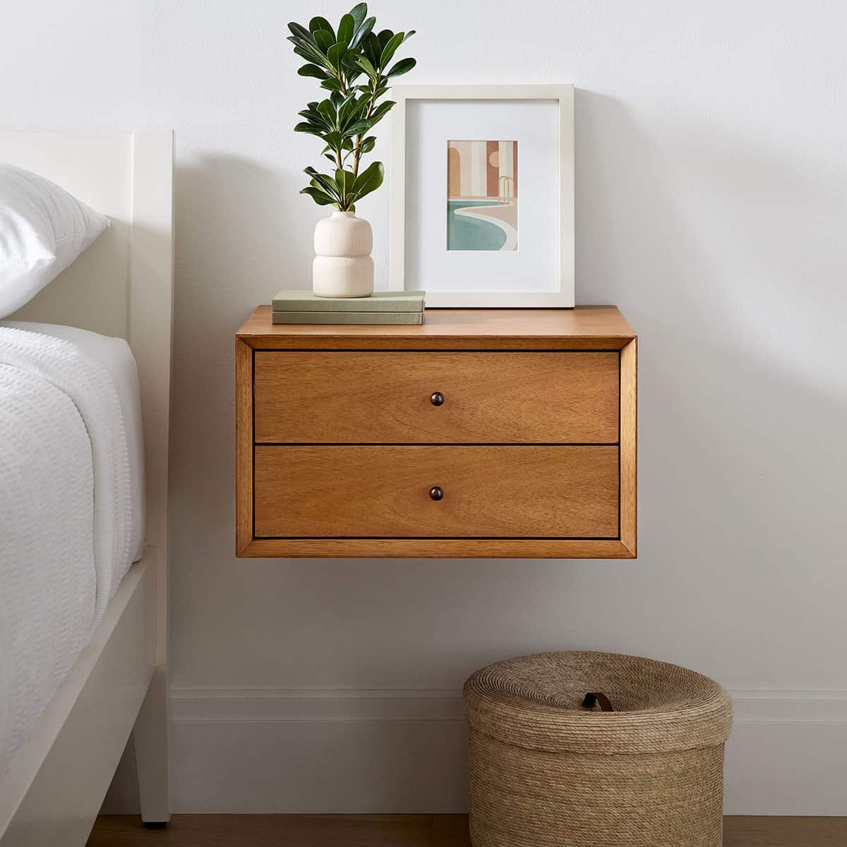 Mid-century style wall-mounted 2-drawer nightstand with modern art piece and plant.