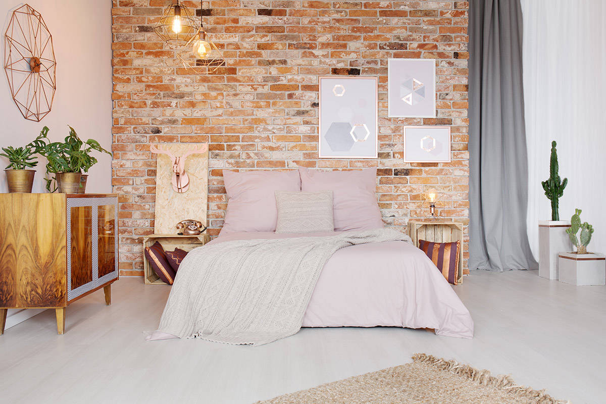 Natural hues in the faux brick feature wall adds warmth to the industrial bedroom design featured here.