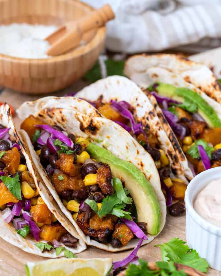 Side view of roasted butternut squash tacos in a tortilla with filling inside.