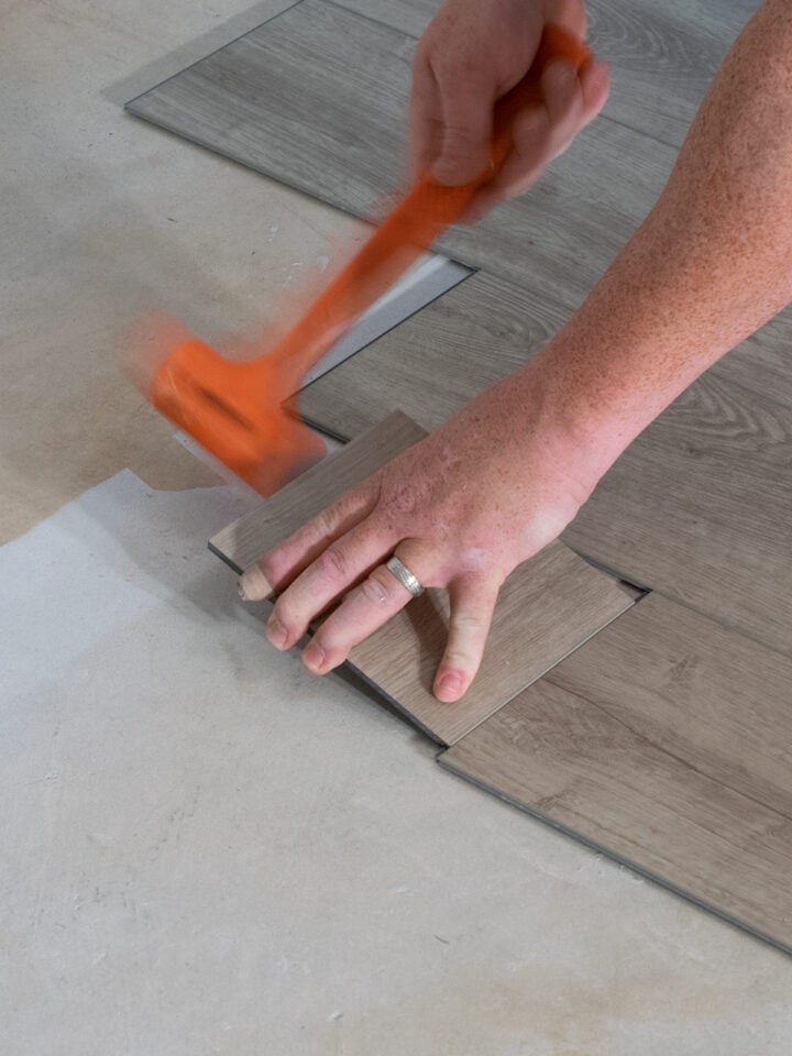 Man using a dead blow hammer to install vinyl plank floor.