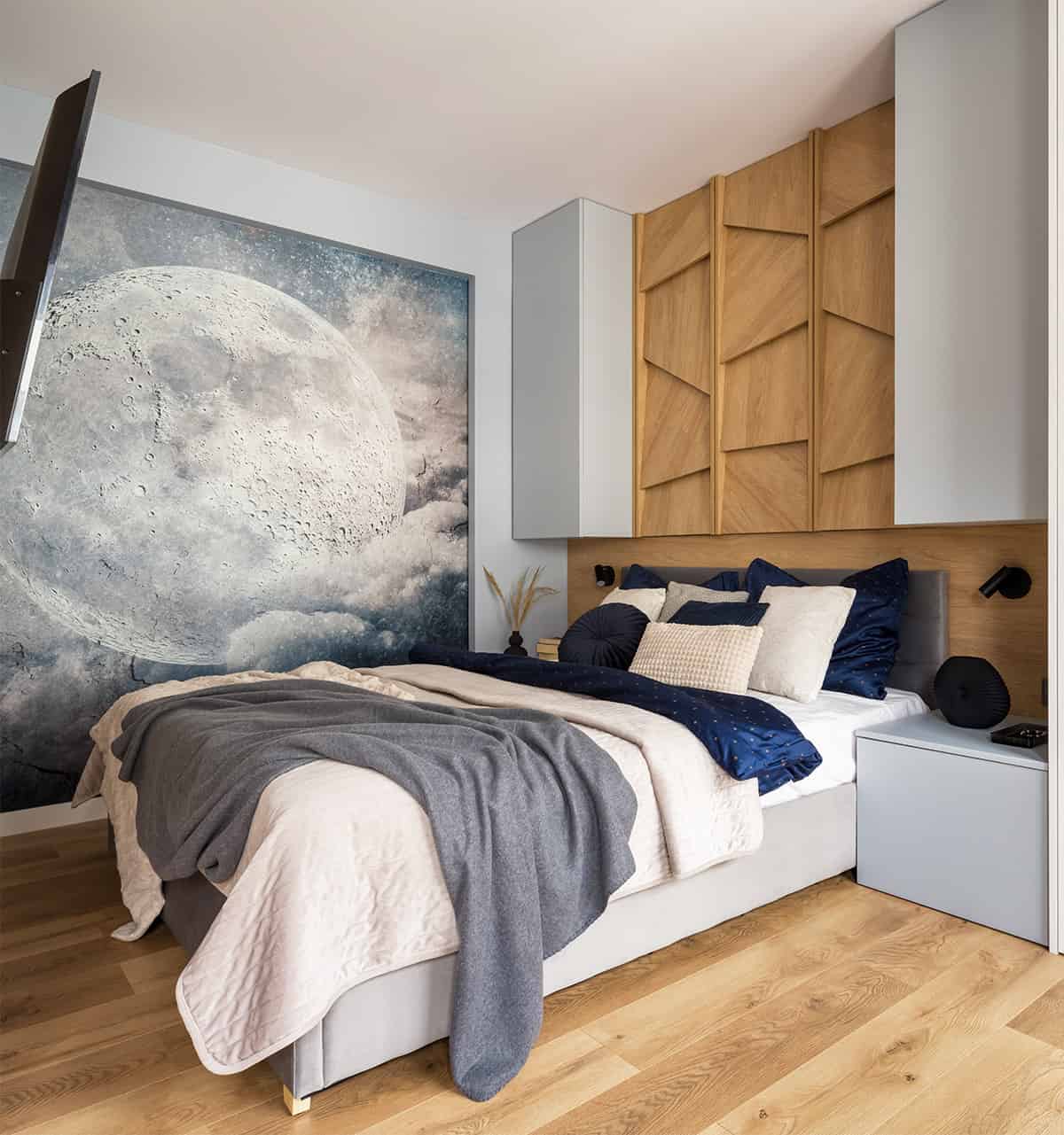 A smoky moon wall mural adds depth to an otherwise light and neutral bedroom space.