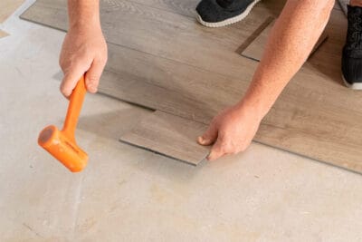 Worker installing vinyl flooring over concrete.