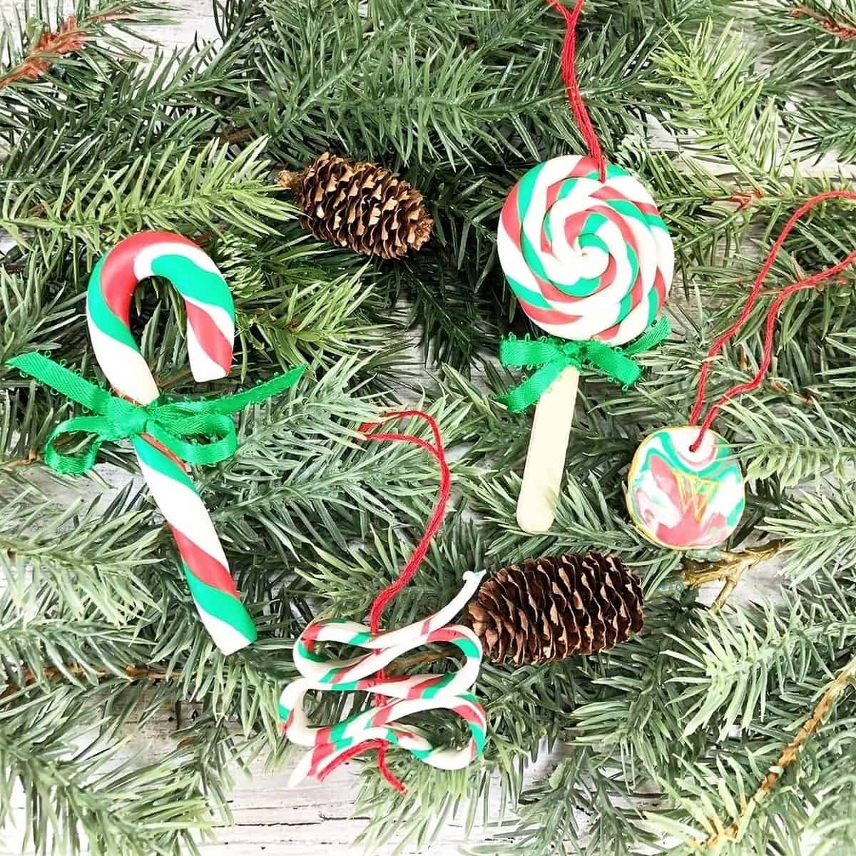 Four red, green, and white candy-cane style polymer clay Christmas tree ornaments including: a taffy style ribbon, a lollipop swirl on a stick, a traditional candy cane style, and a marbled disc.