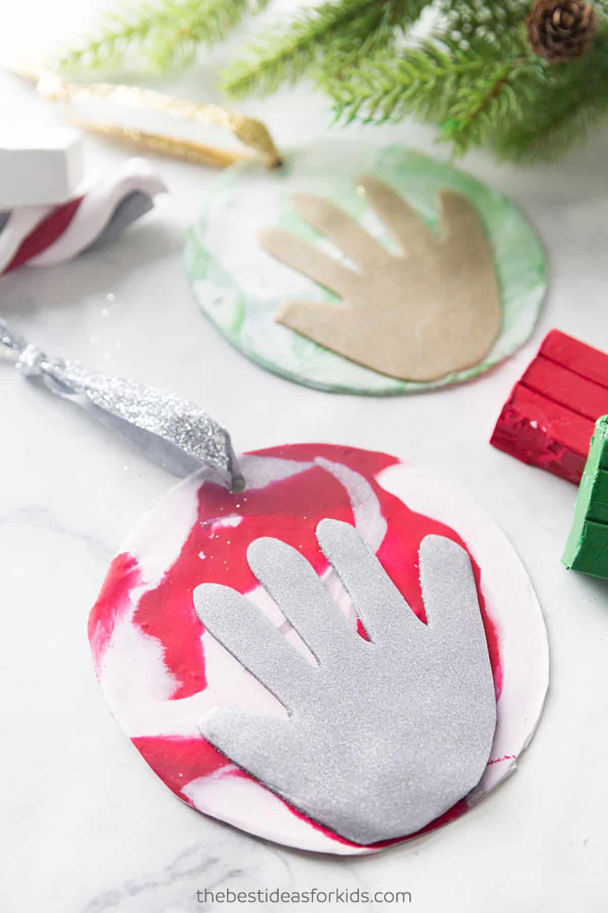 Marbled clay coaster style Christmas tree ornaments in red/white and green/white with silver or gold felt hand print cut outs and corresponding ribbon to match.
