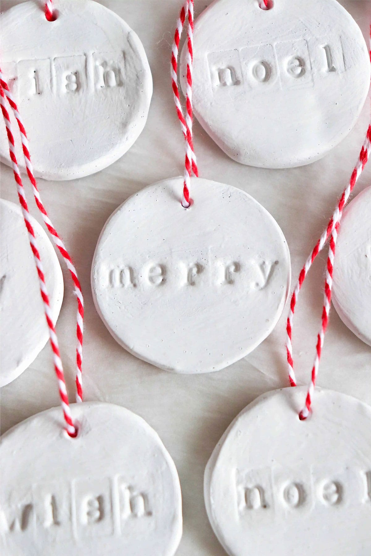 Clay word ornaments Christmas craft white air dry clay letter stamped with red & white baker's twine.