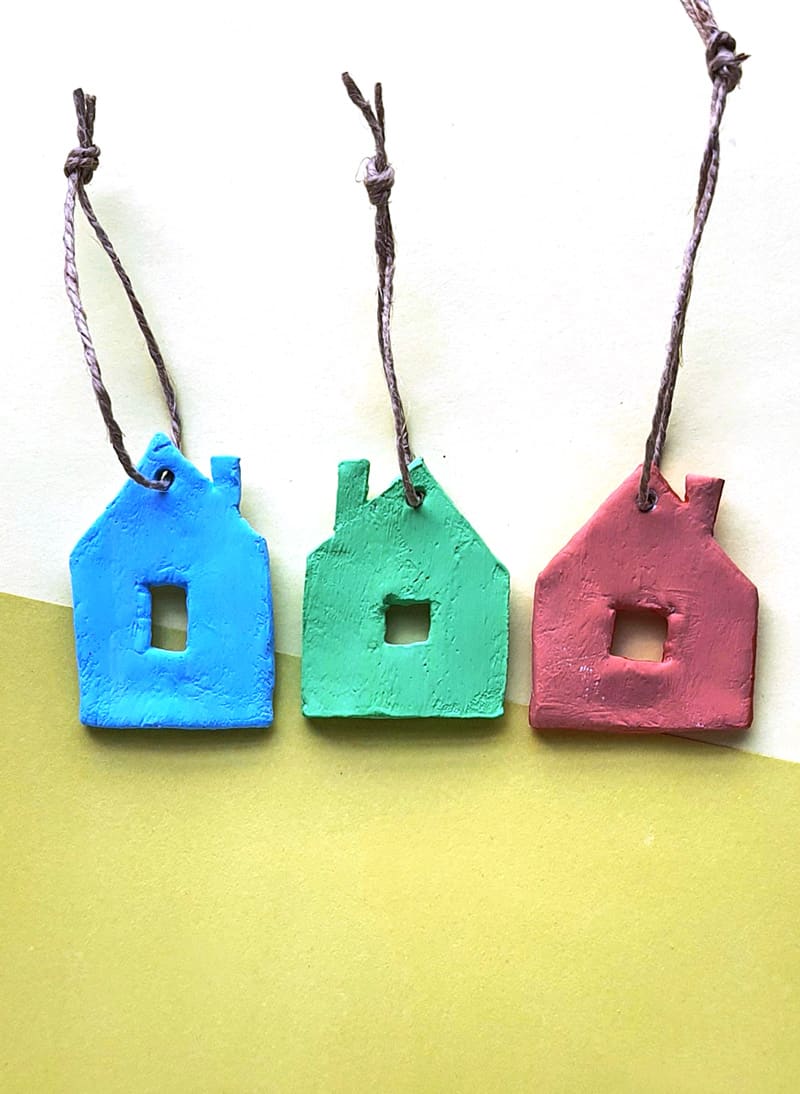 Clay house shaped minimalist Christmas tree ornaments painted in primary colors with leather cords.
