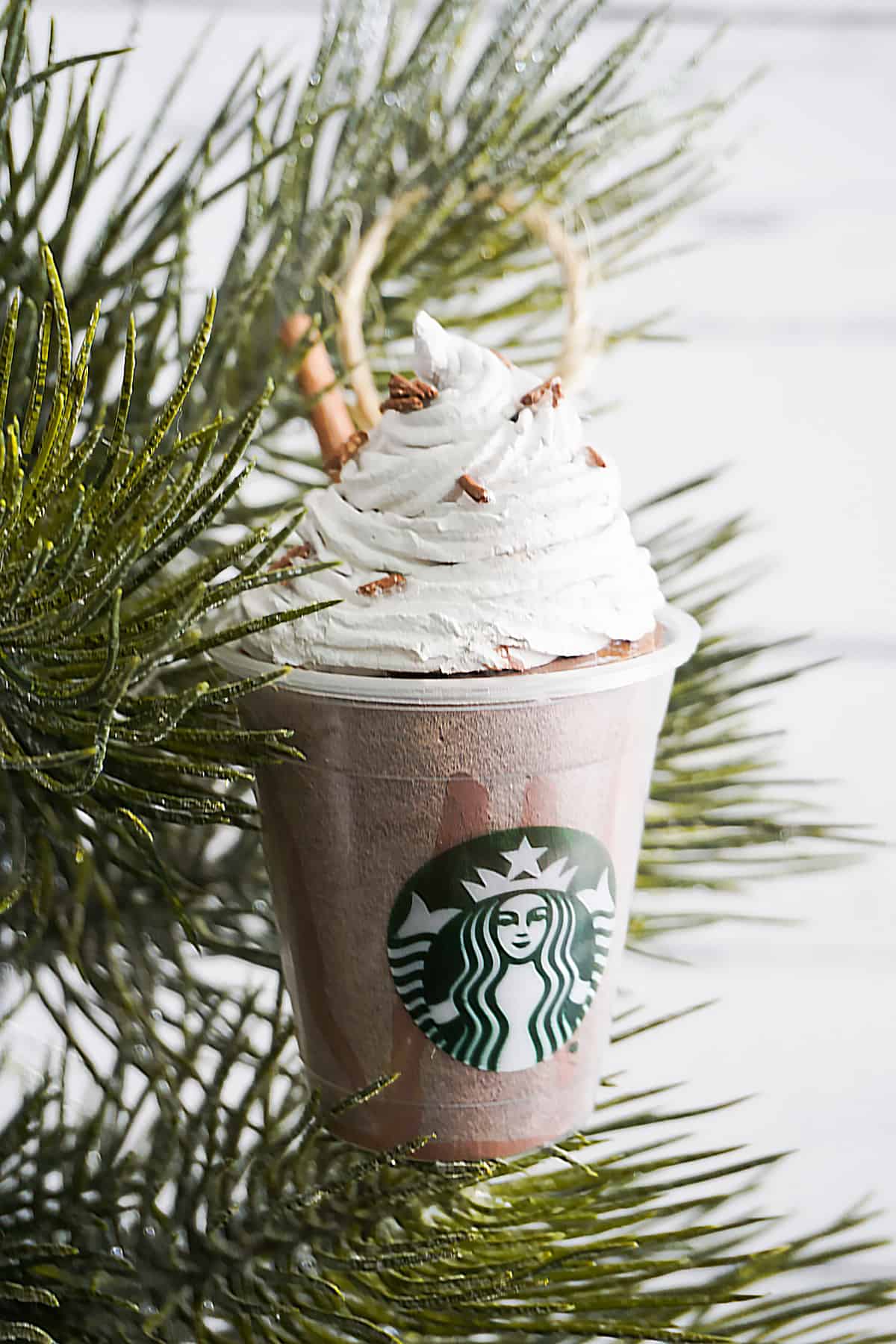 Mock Starbucks Mocha Frappuccinno with whip, chocolate sprinkles and straw Christmas Tree Ornament clay craft hanging from an otherwise bare tree.