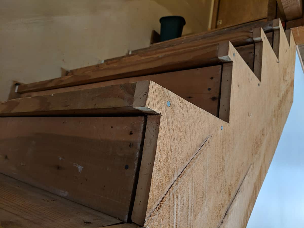 Sideview of warped staircase with gaps in the boards and stringer.