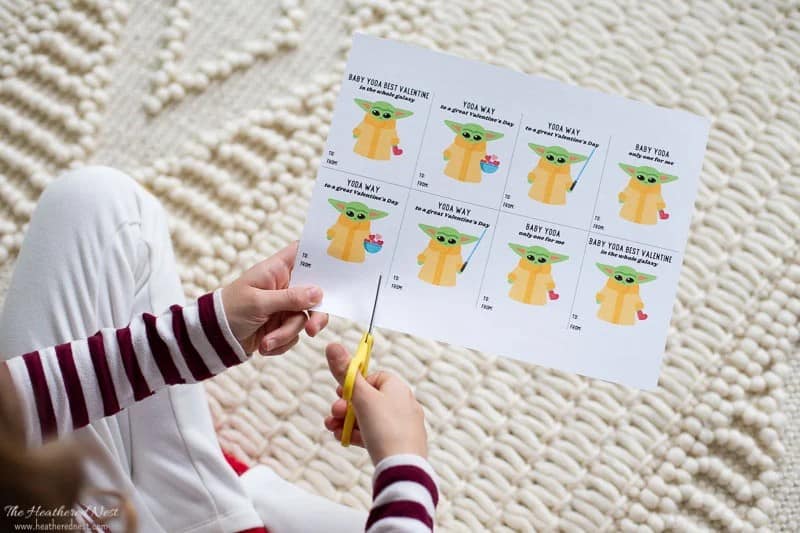 Girl cutting out baby Yoda Valentine's Day cards printable.